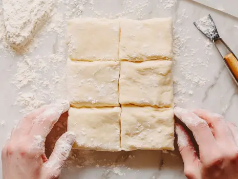 Folding laminated dough for Gipfeli on a floured surface.